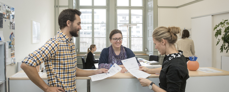 Bannerbild LLBM - Mitarbeitende und Studierende am Infodesk im Sekretariat